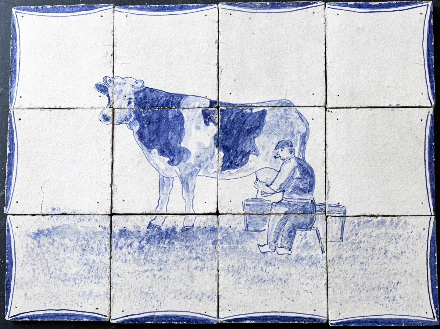 Antique Delft blue tile panel showing a farmer milking