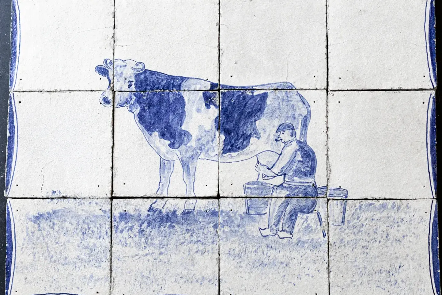 Antique Delft blue tile panel showing a farmer milking