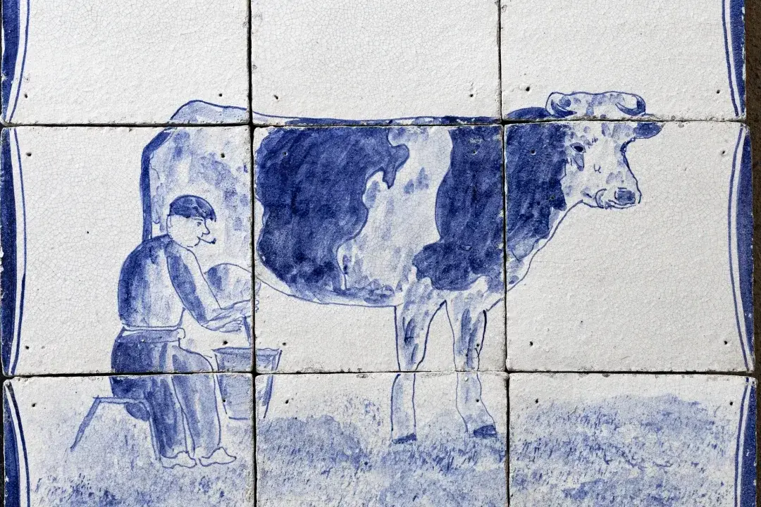 Traditional Dutch tile panel showing a farmer milking