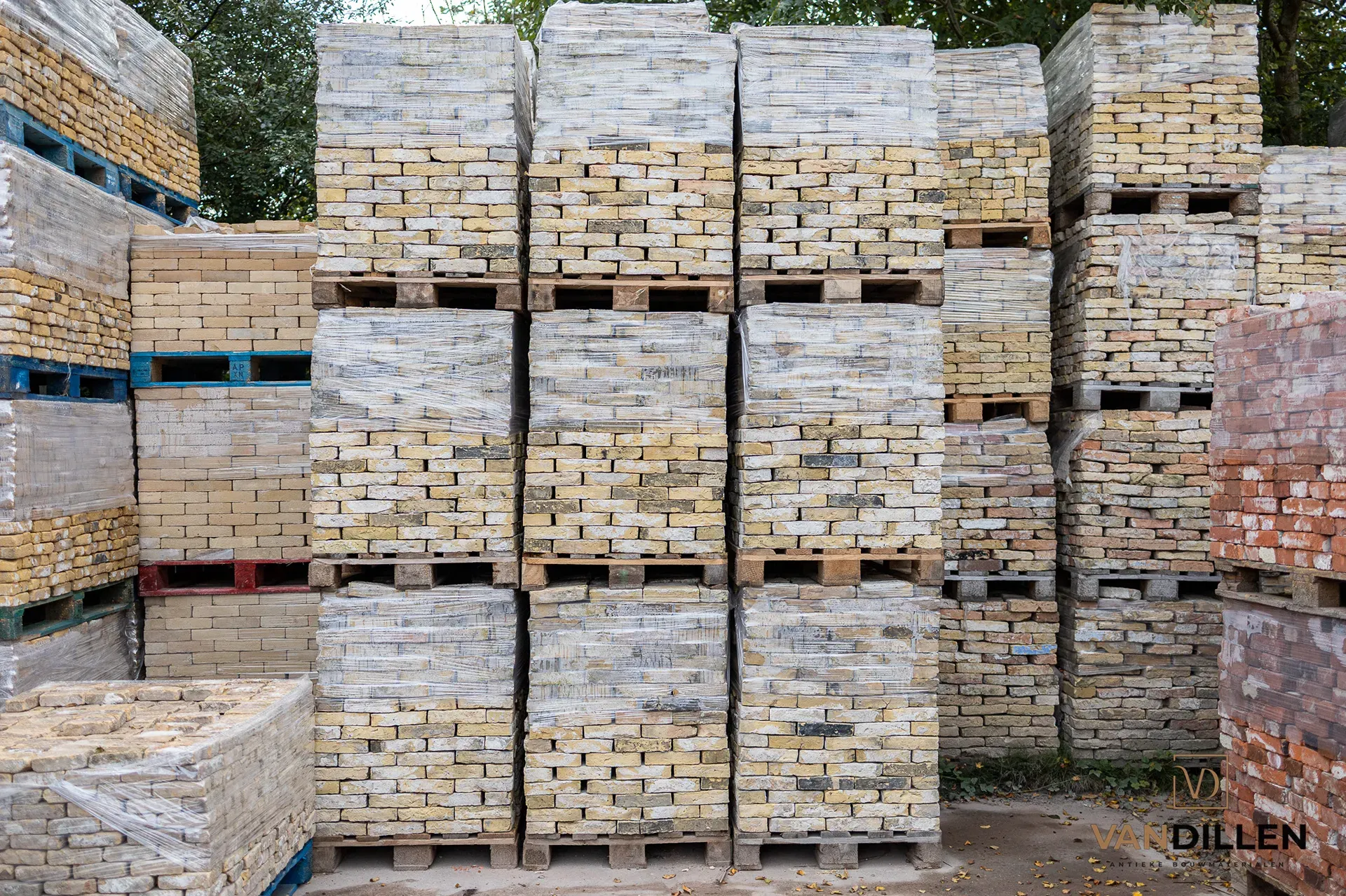 Pallets met oude gele bakstenen op het opslagterrein